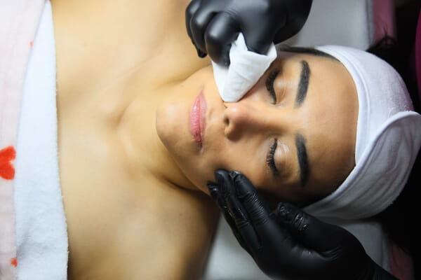 Studio owner applying skincare treatment at a Costa Rica esthetics salon, natural window light